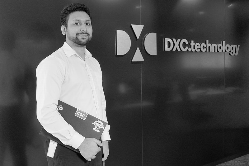 NiloyChowdhury, DXC Graduate with his laptop with DXC backdrop