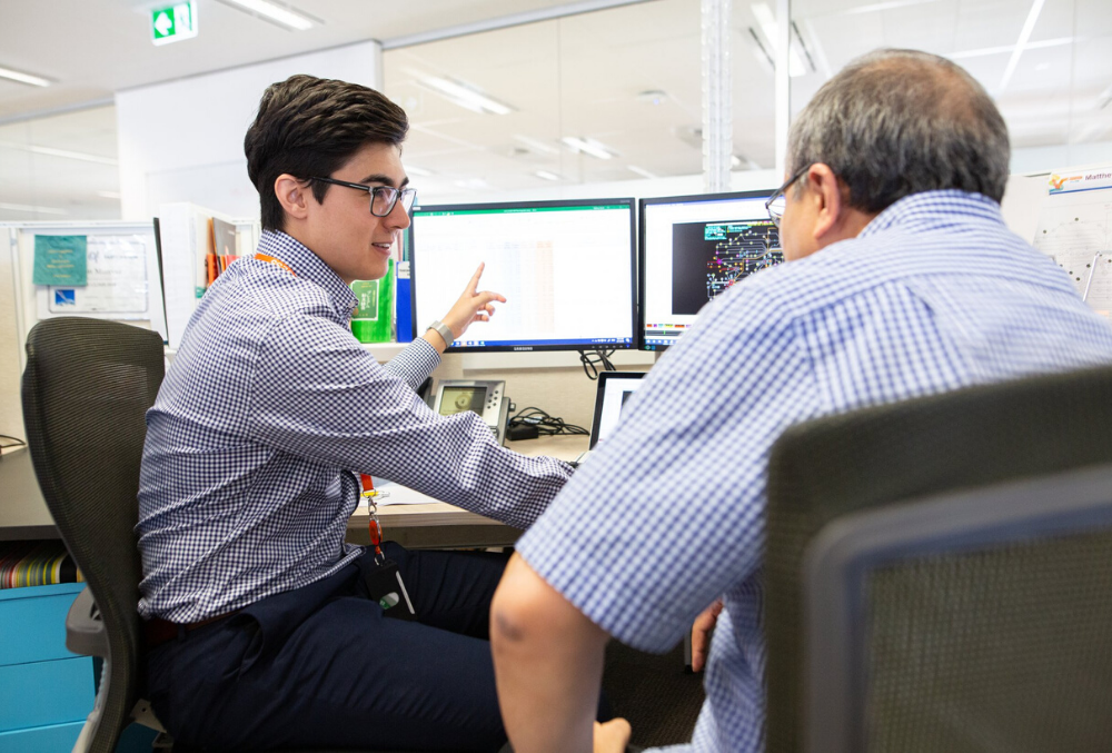 Matthew having a discussion with colleague at his desk