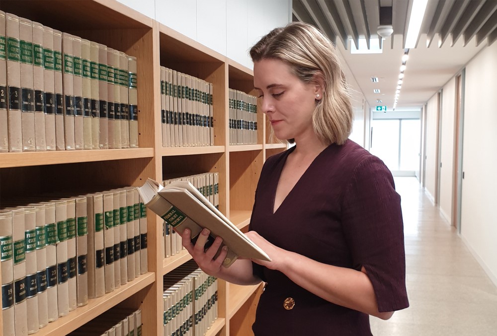 AGD Graduate - Young female lawyer reading a book at the library.