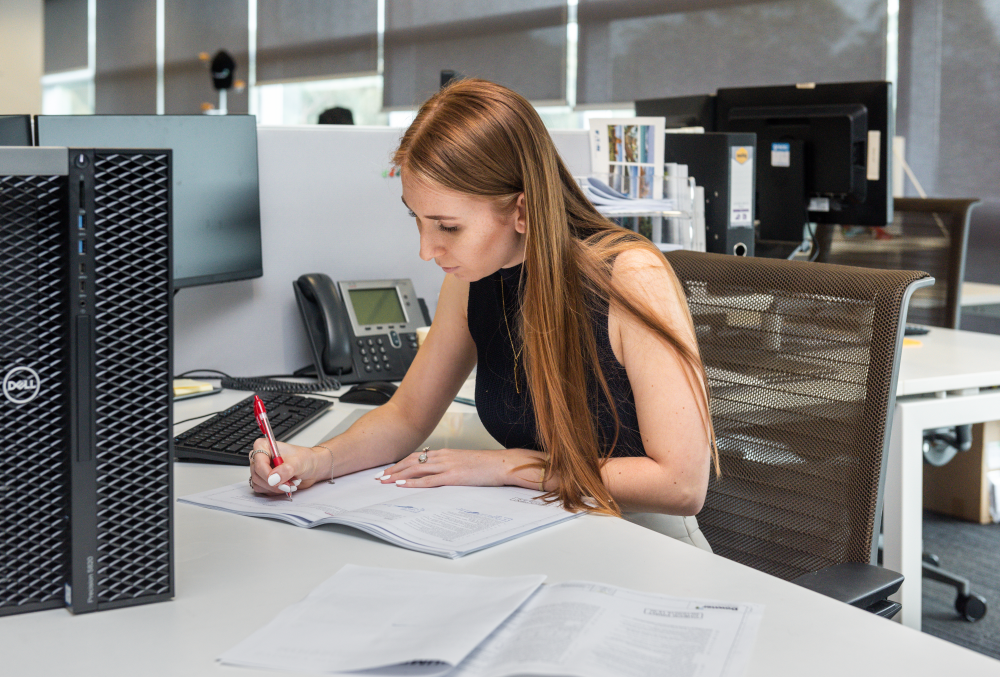 Downer Graduate- Young female executive writing on her desk.