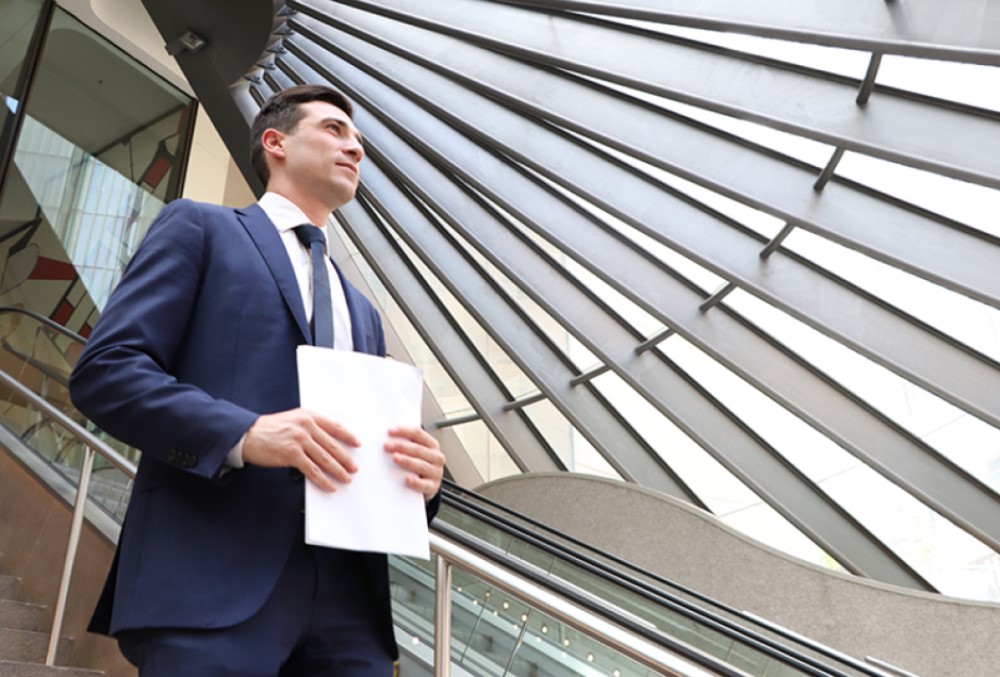 Sparke Helmore Lawyers Graduate - Young male lawyer walking downstairs with files on his hands.
