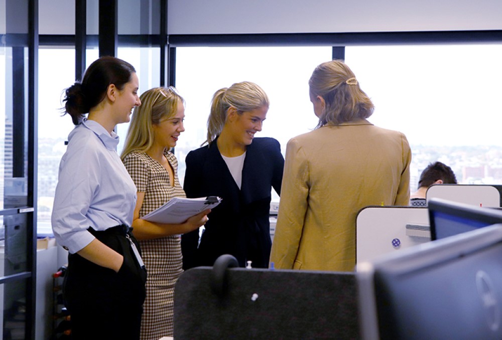 Sparke Helmore Lawyers Graduate - Young female lawyer discussing with her colleagues.