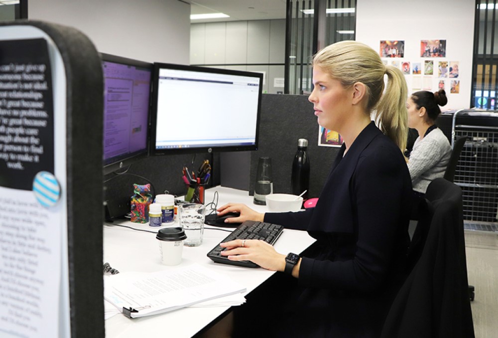 Sparke Helmore Lawyers Graduate - Young female lawyer sitting on her desk.