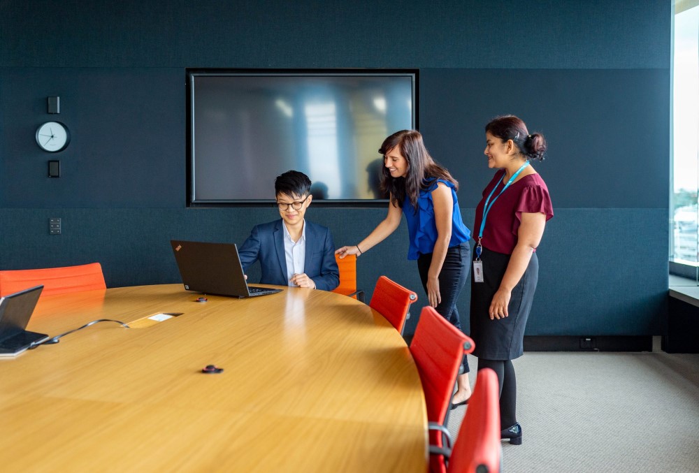 The Data School Graduate - Female professional meeting with her team.