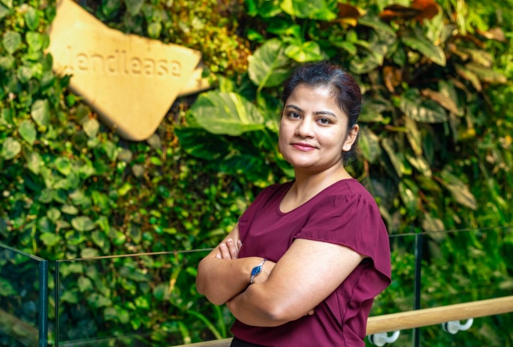 The Data School Graduate - Female professional standing near a wall cover with plants.
